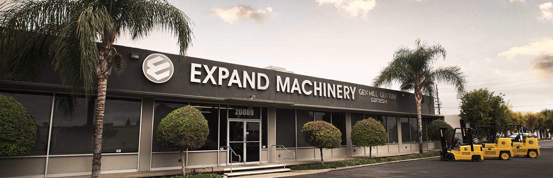 Front of a building with "expand machinery' in large letters above the front door. 